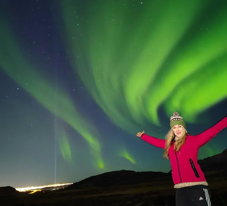 Viajera celebrando bajo auroras boreales en Islandia